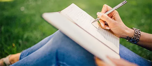 a woman sitting in grass and journaling